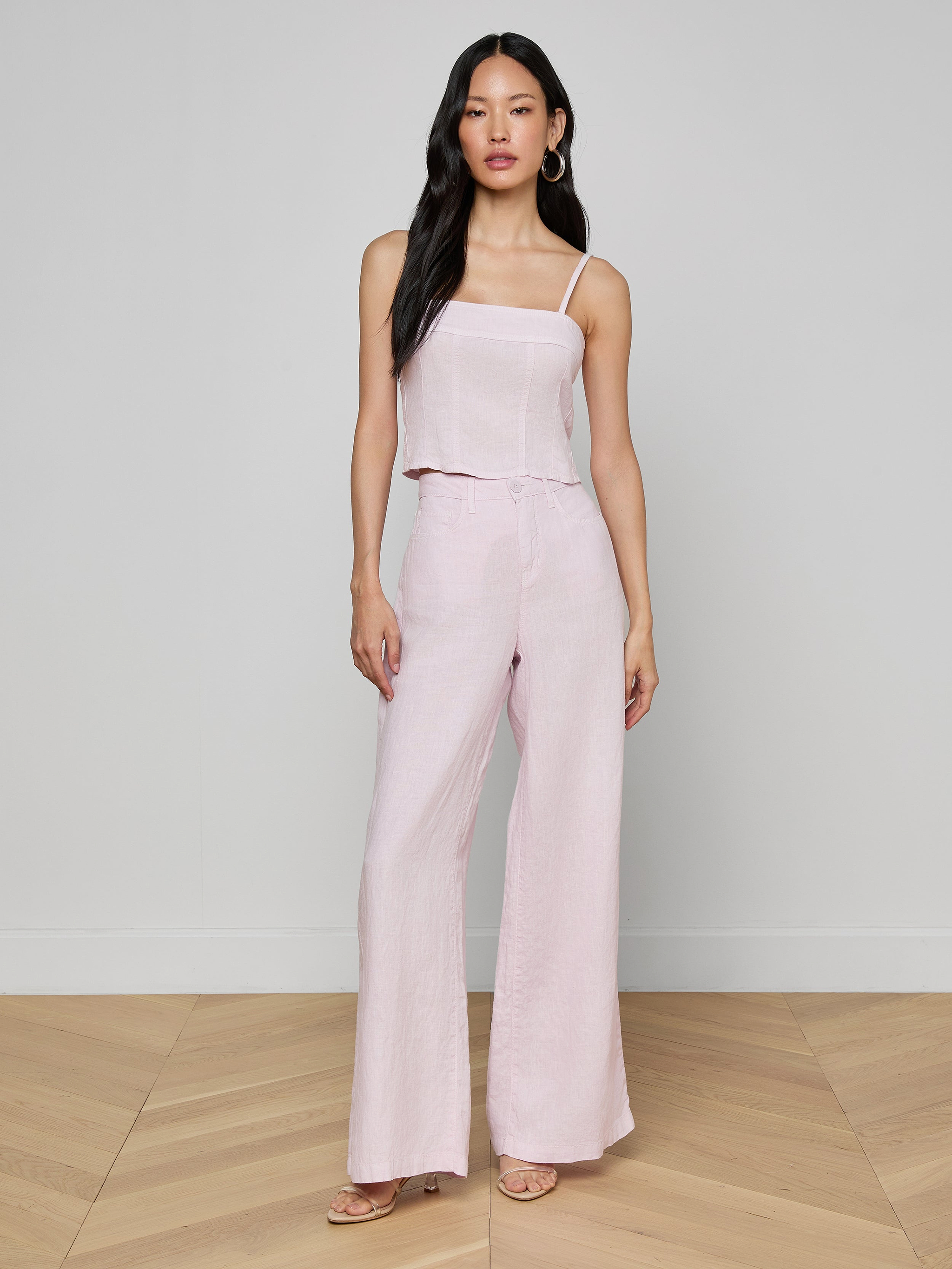 A woman wearing the Arlin Linen Tank in light pink paired with matching wide-leg pants, standing against a plain, light background and facing forward with a neutral expression.