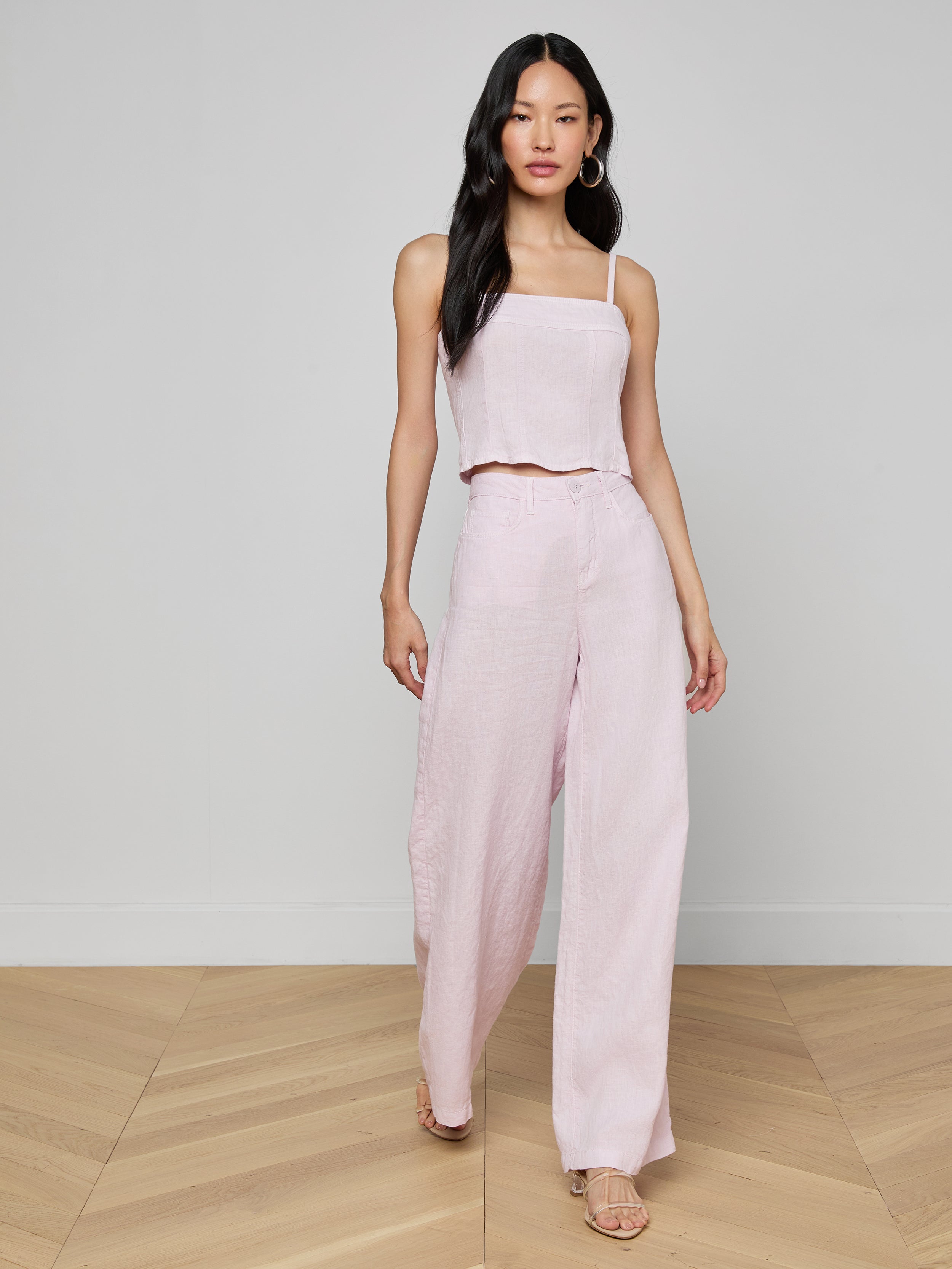A woman wearing the Arlin Linen Tank in light pink paired with matching wide-leg pants walks forward against a plain white background.