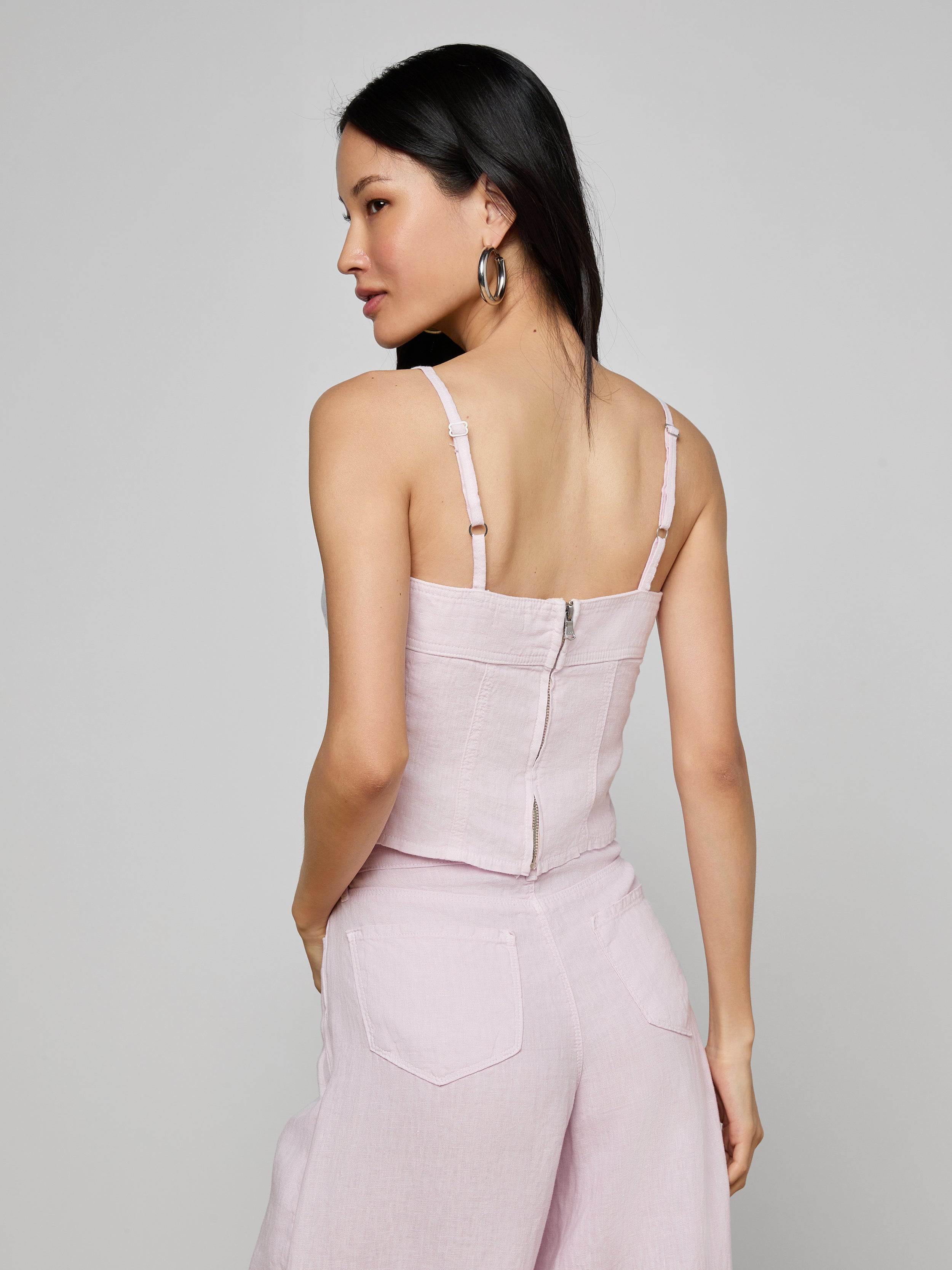 Woman with long black hair wearing the Arlin Linen Tank in light pink, paired with matching wide-leg pants, shown from the back against a plain light background.