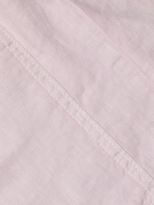 Close-up of light pink linen fabric with a diagonal seam and stitching, showcasing the texture and weave—ideal for the Arlin Linen Tank.