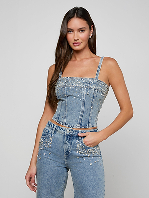 Woman wearing a sparkly denim top and jeans on a plain background