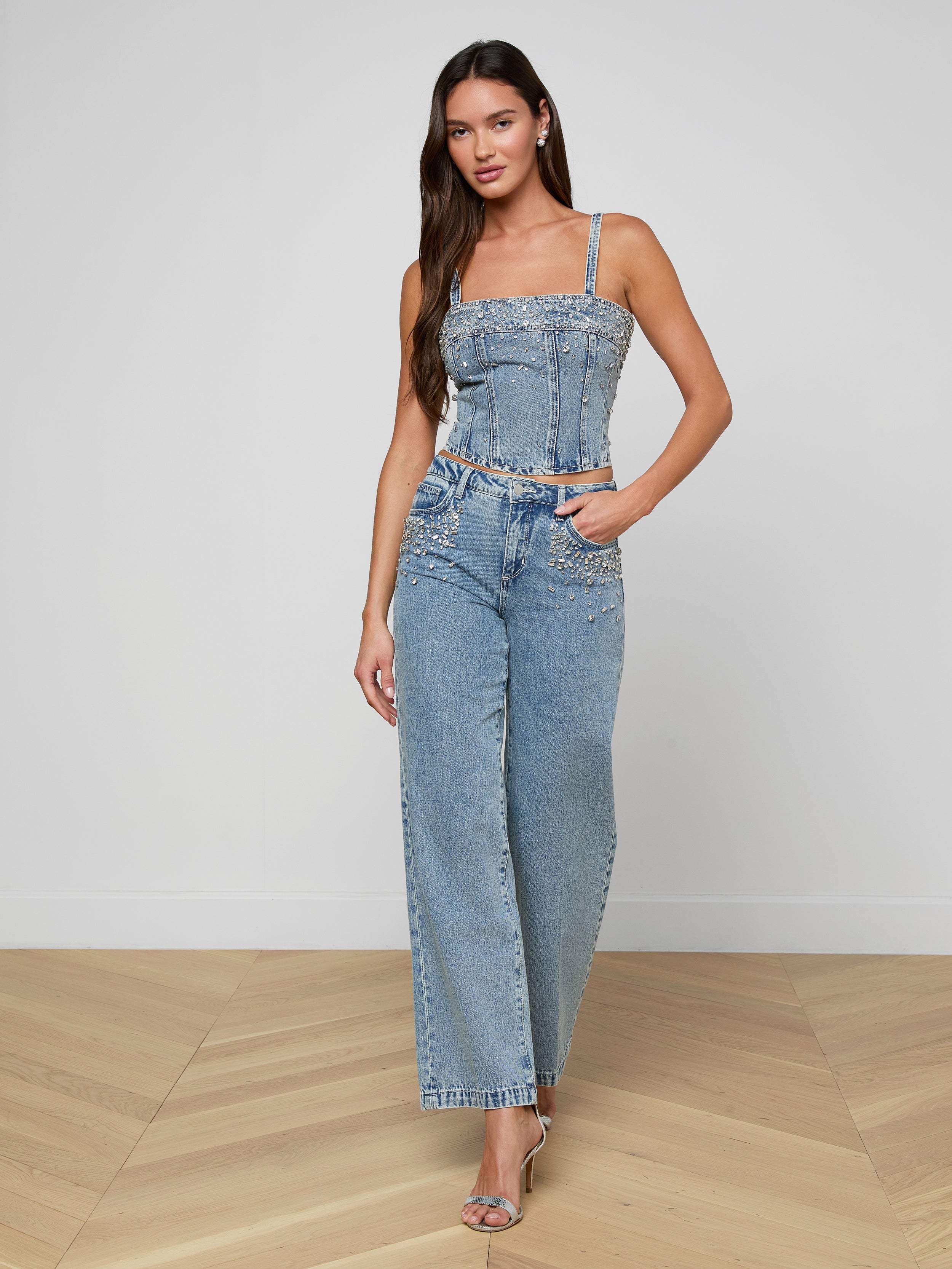Woman wearing a denim embellsihed top on a plain background