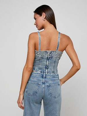 Woman wearing a denim embellsihed top on a plain background