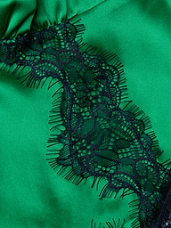Close-up of the Kimber Silk Lace Camisole, showcasing green satin fabric with a black lace trim adorned with a floral pattern and delicate fringe.