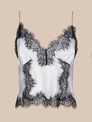 The Kimber Silk Lace Camisole is a cropped top with thin straps, a deep V-neckline, and intricate black lace trim at the neckline, hem, and front, shown against a plain beige background.