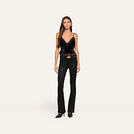 A woman with long brown hair and a neutral expression stands against a plain background, wearing the Kimber Velvet Lace Camisole, paired with black fitted jeans, a belt, and black pointed-toe boots.