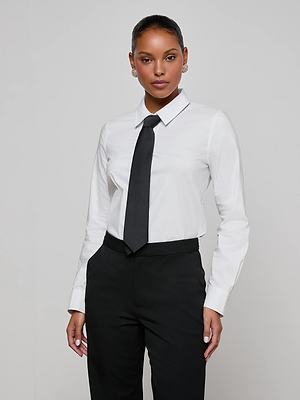 A woman wears the Blake Bodysuit, featuring a removable tie, with black pants. She stands confidently against a plain light gray background, looking at the camera with her hands by her sides.