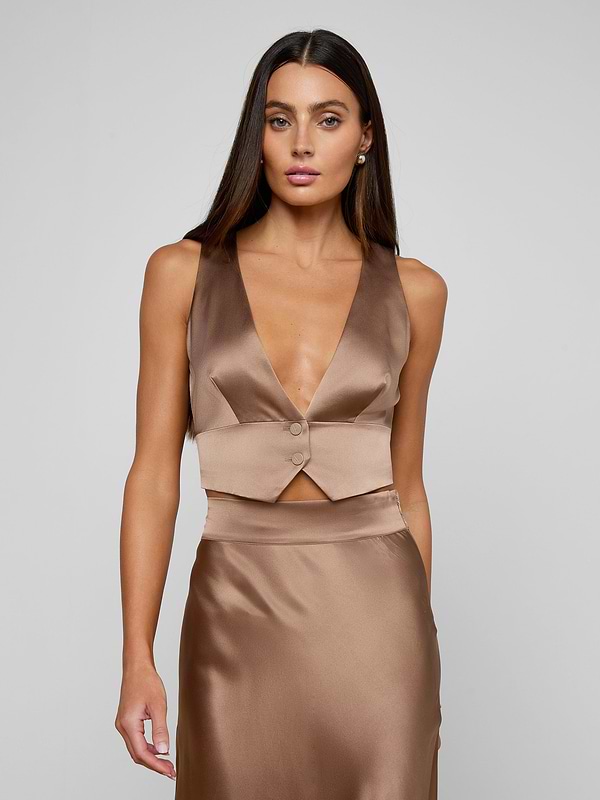 A woman wearing the Devony Silk Vest with a plunging neckline and matching satin skirt stands against a plain light background, looking directly ahead with a neutral expression.