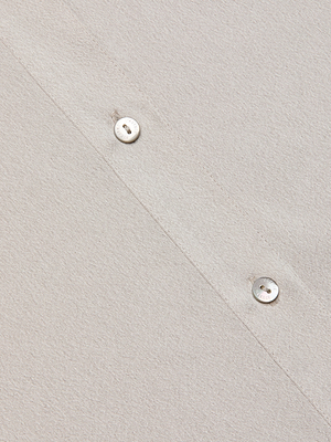 Close-up of the Capri Lace Sleeve Blouse in light beige, featuring a relaxed fit, diagonal stitching, and two white buttons. The soft textured fabric offers effortless style and comfort.