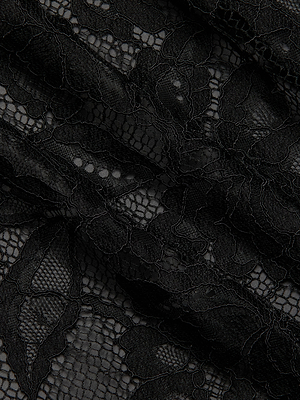 Close-up of delicate black lace fabric with an intricate floral pattern and textured leaf designs, featured on the Rhett Oversized Lace Blouse. Ideal for adding elegance to any outfit or as a statement piece in your wardrobe.