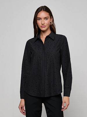 A woman wears the L'AGENCE Ellery Crystal Shirt, a black rhinestone-embellished long-sleeve blouse, with black pants against a light grey background.