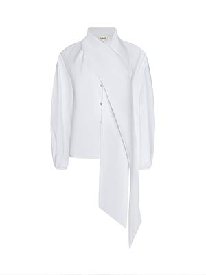 The Deon Tie-Neck Blouse is a white oversized blouse in organic cotton poplin, featuring a high neck, blouson sleeves with gathered cuffs, an asymmetrical draped scarf detail down the front, and subtle buttons.