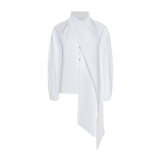 Introducing the Deon Tie-Neck Blouse: a white long-sleeve design crafted from organic cotton poplin, featuring a dramatic asymmetrical draped panel cascading from the collar down the front. This blouse boasts a button-up closure, blouson sleeves, and an elegant modern silhouette reminiscent of an oversized neck tie.