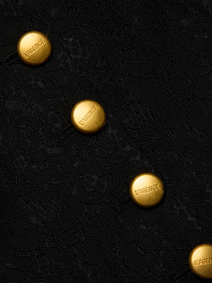 Close-up of the Kino Lace Vest’s black textured fabric, highlighted by four irregularly placed round gold 