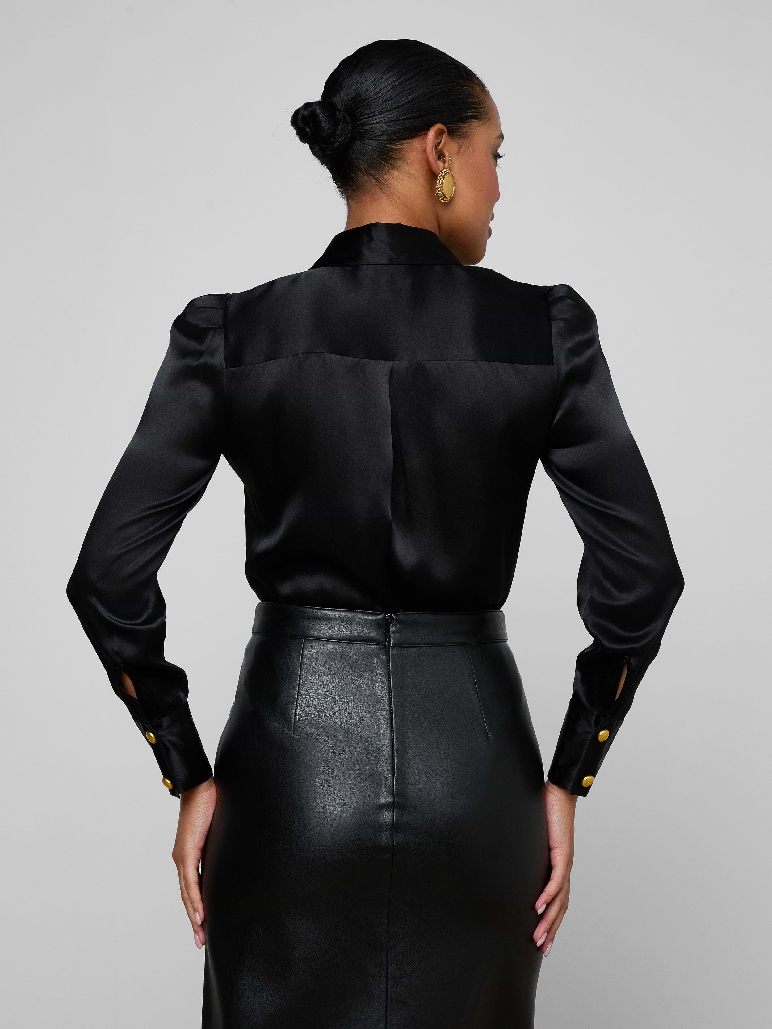 A woman is shown from the back wearing the Honey Silk Blouse, styled with a high-waisted black leather skirt, standing against a plain light background.