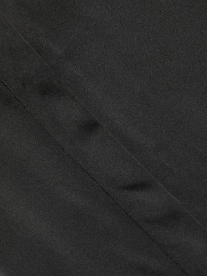 Close-up of the Honey Silk Blouse in black, featuring a diagonal seam that highlights the smooth texture and elegant folds of its luxurious silk fabric.