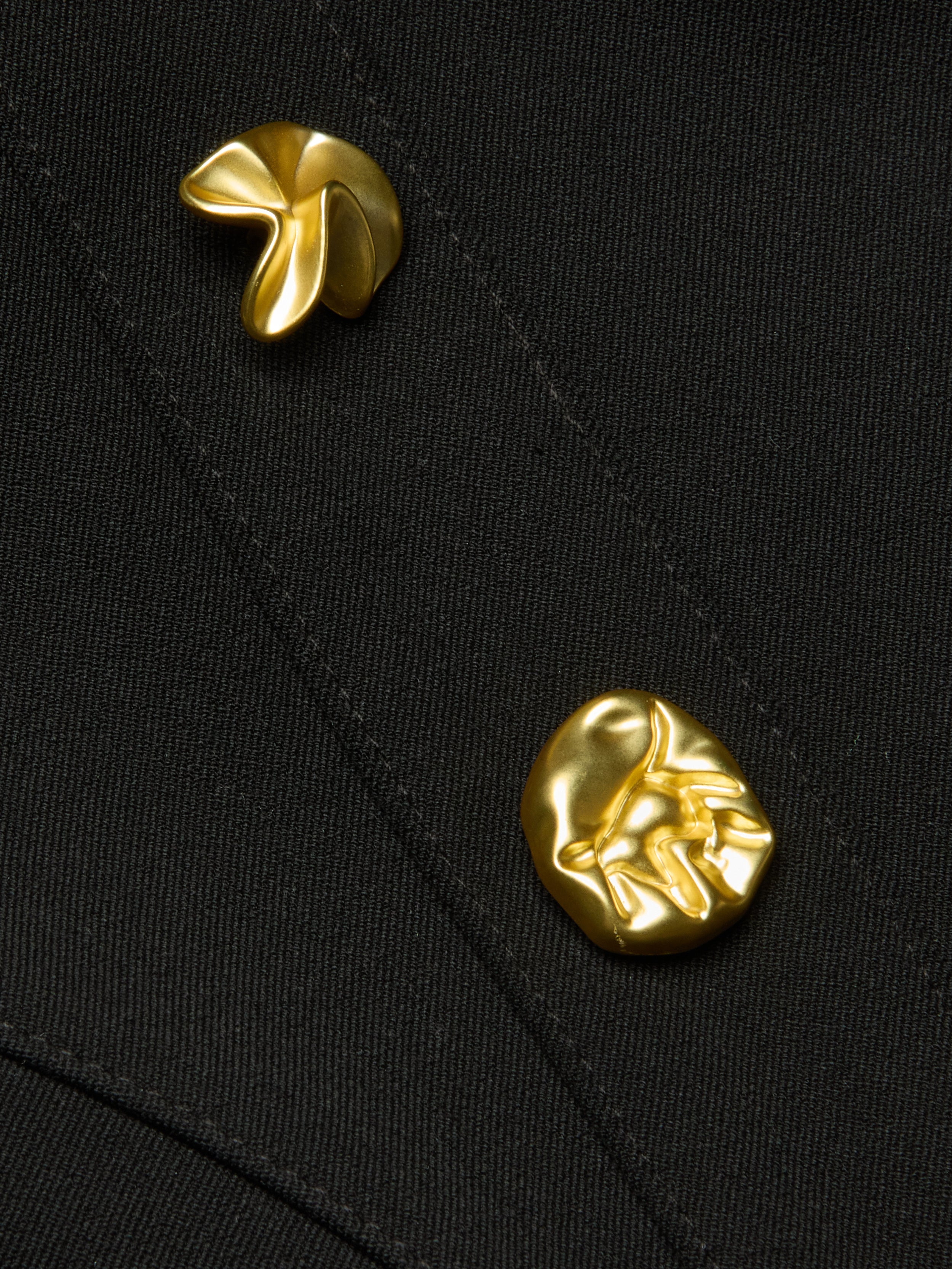 Two irregularly shaped, shiny gold pins are attached to the Anna Corset Top’s black fabric with diagonal stitching. Featuring a smooth, sculptural appearance and organic forms, the pins enhance the high-fashion silhouette of this going-out top.
