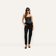 A woman wearing a black satin Meliora Corset Peplum Top with black trousers and heels.