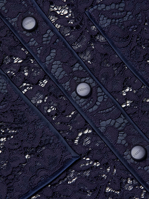 Close-up of the Roelle Lace Blouse: a sheer navy top with intricate floral lace, scalloped edges, and vertically aligned gold buttons engraved with “L’AGENCE PARIS.”.