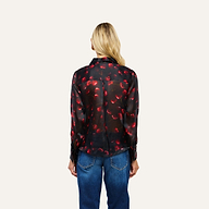 A person seen from behind, wearing a Sona Silk Blouse in black with a red cherry print and casual blue jeans.