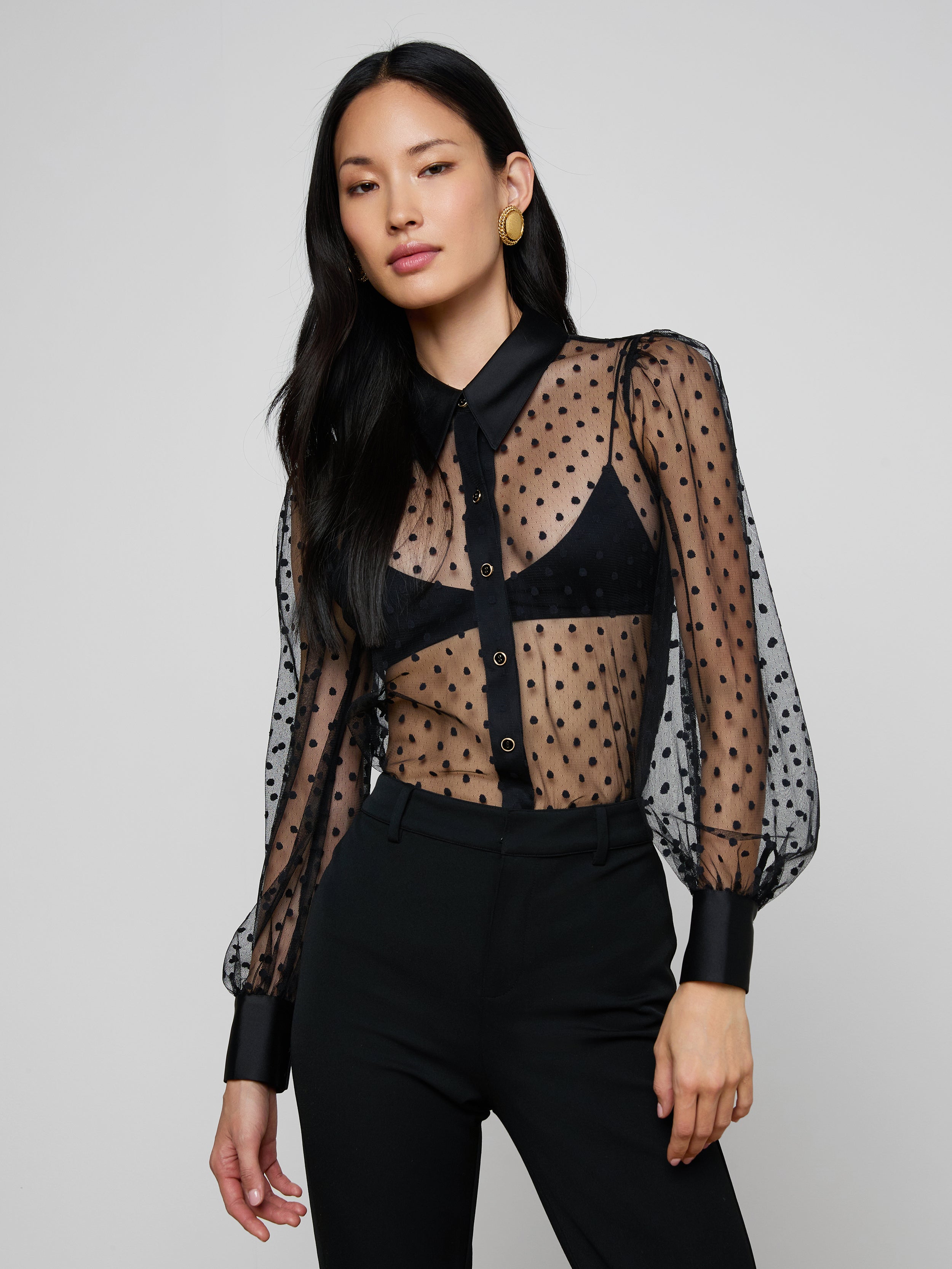 A woman in the Sophie Long-Sleeved Blouse, featuring black sheer Swiss dot fabric.