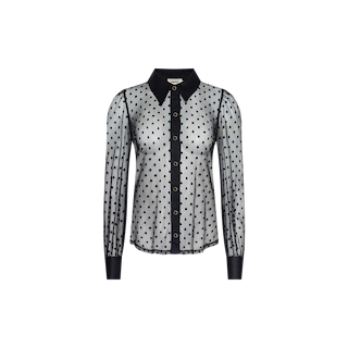 The Sophie Long-Sleeved Blouse is crafted from sheer Swiss dot fabric with a delicate polka dot pattern and features long sleeves, a pointed collar, and black buttons down the front. Its transparent design is complemented by solid black accents at the cuffs, collar, and button placket for an elegant, feminine finish.