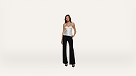 A woman stands against a plain white background, wearing a white spaghetti strap top, black flared pants, and black heels, with one hand in her pocket.