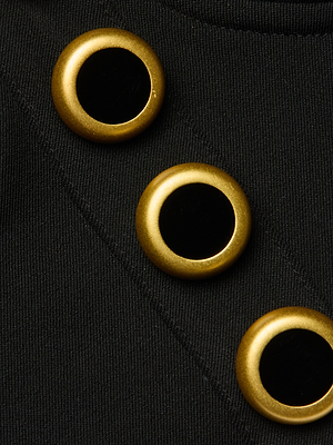 Close-up of the Sophia Chain Bralette featuring three shiny, round gold buttons with black centers on black stretch suiting fabric, arranged diagonally.