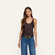 A person wearing an Eddie Satin Tank in black with a red cherry print, blue jeans, and a black belt.