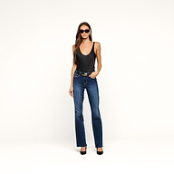 A woman wearing black sunglasses, the Eddie Tank bodysuit with a scoop neckline, blue straight-leg jeans, a belt, and black heels stands against a plain white background.