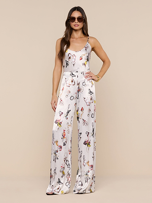 Woman wearing the Charmy Satin Camisole with sunglasses, posing against a beige background with one hand on her hip.