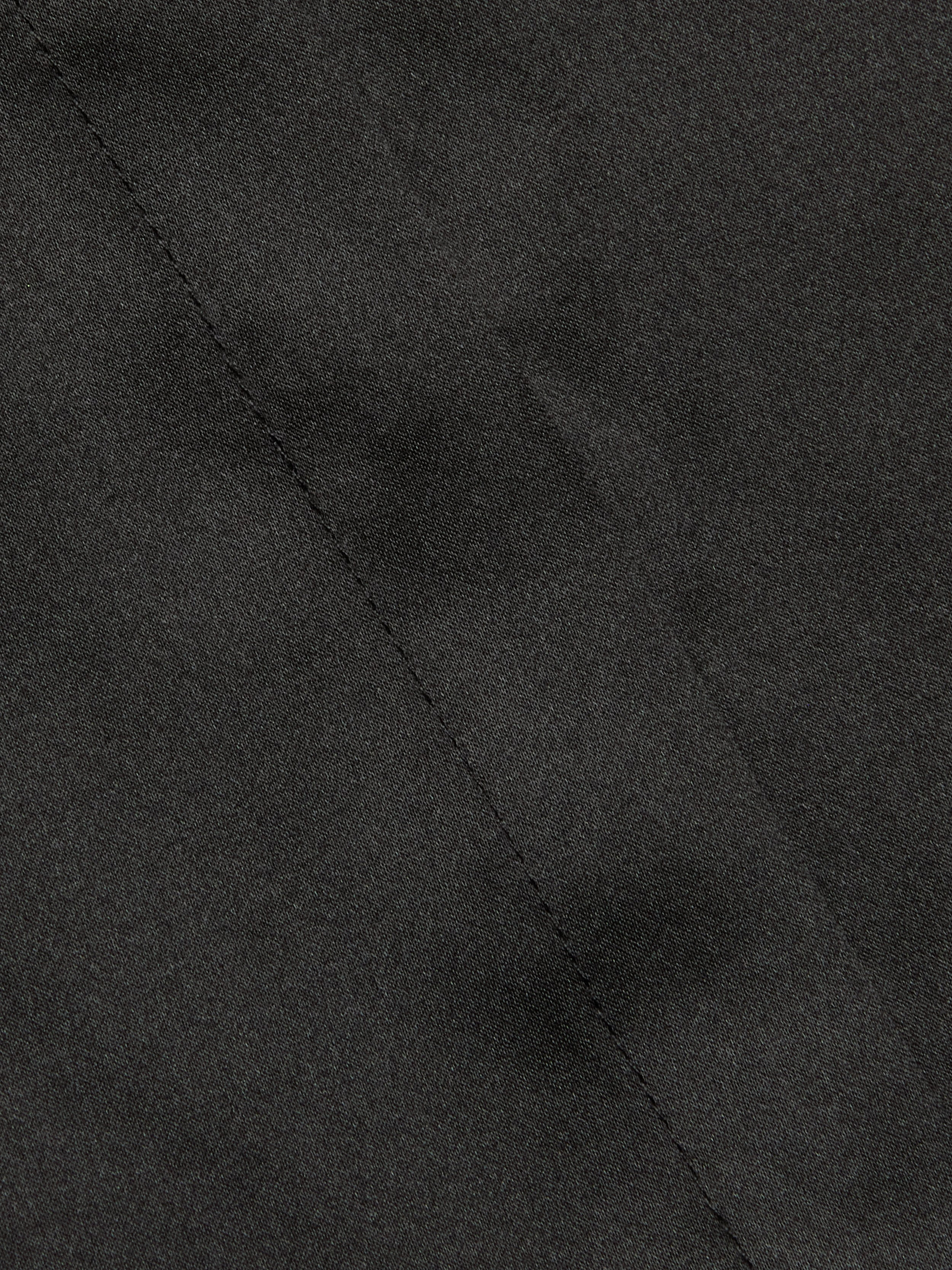 Close-up of the Phoebe Silk Blouse in black silk charmeuse, featuring a visible diagonal seam through the center that highlights the fabric’s texture and intricate stitching detail.