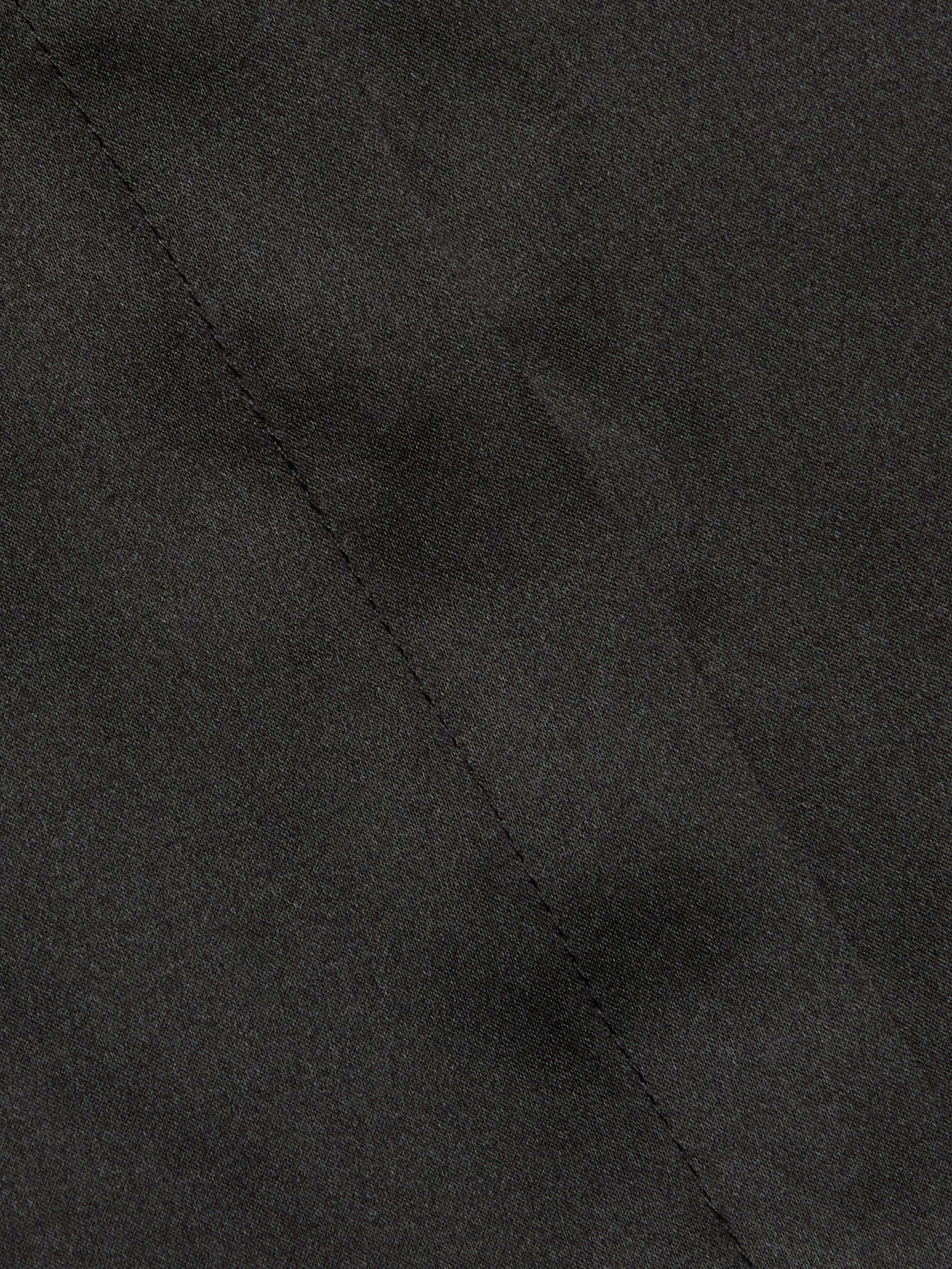 Close-up of the Phoebe Silk Blouse in black silk charmeuse, featuring a visible diagonal seam through the center that highlights the fabric’s texture and intricate stitching detail.