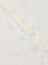 Close-up of the Phoebe Silk Blouse in a light-colored silk charmeuse, featuring a diagonal seam that highlights its smooth texture and subtle stitching detail.