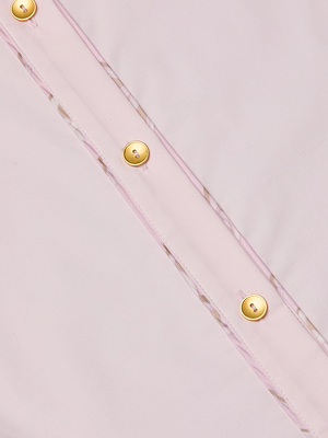 Close-up of the Fawn Shirt, a light pink organic cotton blouse with gold buttons and visible stitching details.