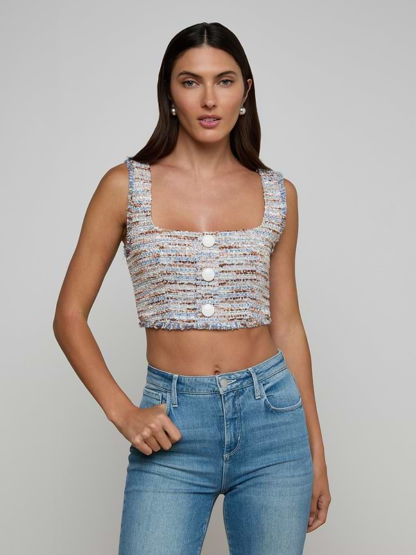 A woman with long dark hair wears the Muno Tweed Top, a textured cropped style with large buttons, paired with high-waisted blue jeans against a plain light gray background.