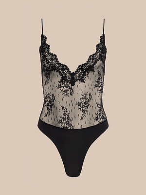 The Kaelith Lace Bodysuit features sheer black lace, adjustable straps, a scalloped V-neckline, Chantilly floral lace bodice, and solid black lower section, shown on a beige background.