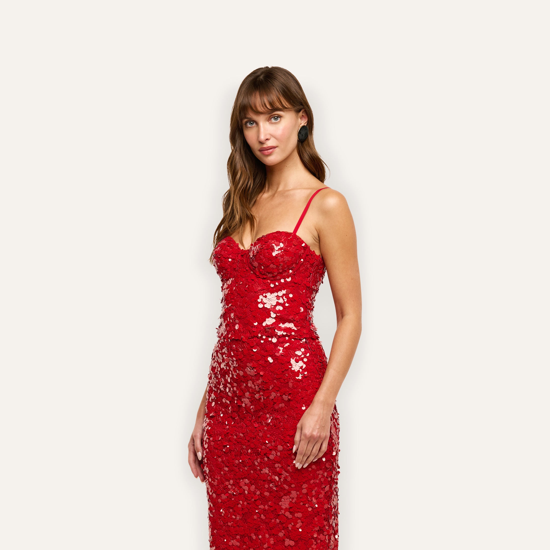 A woman wearing a Lior Sequin Top, featuring a red sequin bustier with thin straps and structured cups.