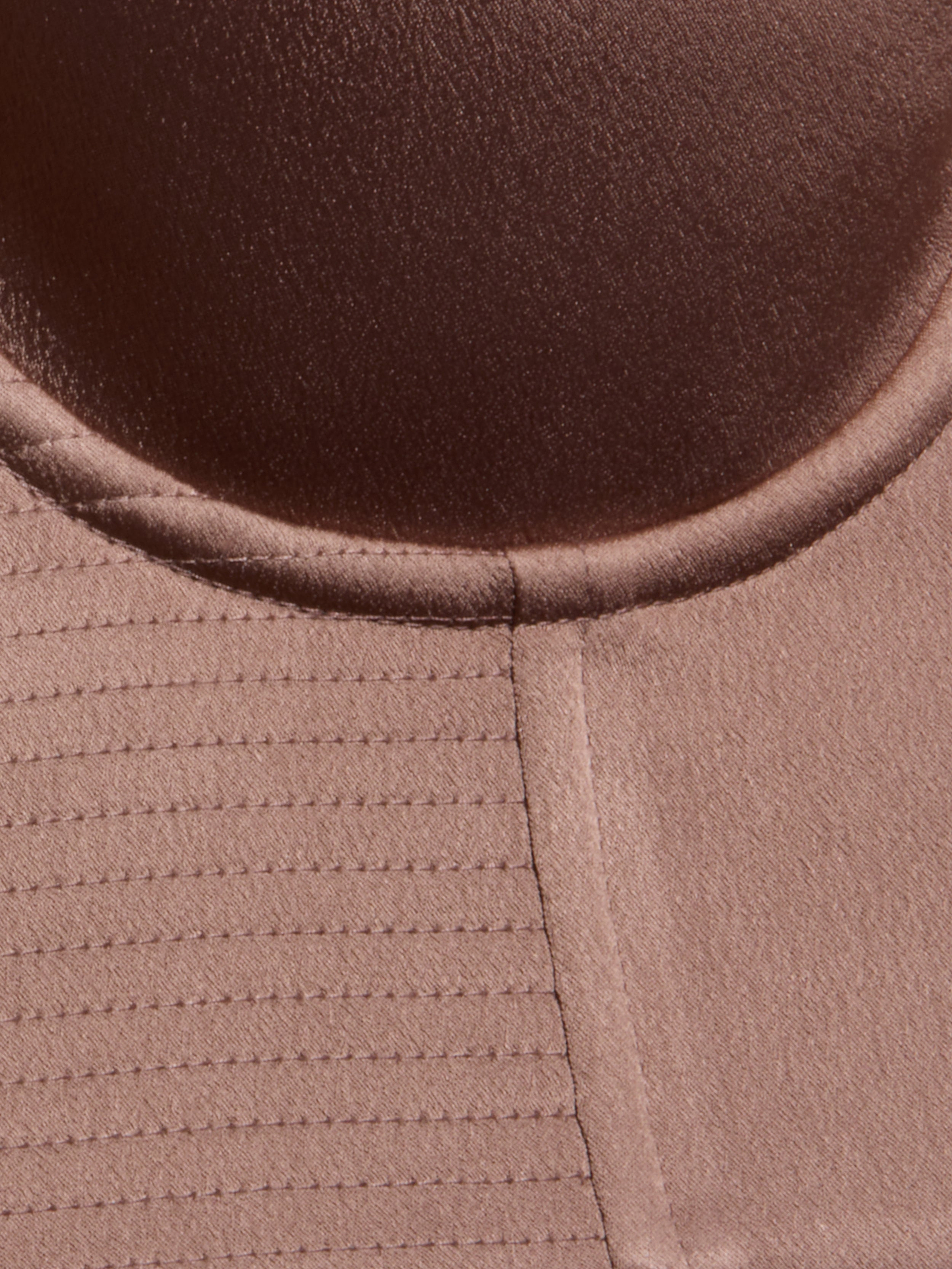 Close-up of a brown fabric with a circular seam at the top and parallel stitched lines on the left, showing texture and stitching details from the Nysa Bustier Top.