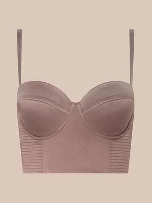 The Nysa Bustier Top is a mauve, structured bralette featuring thin adjustable straps, molded cups for support, and ribbed detailing on the top edge and sides, shown against a beige background.