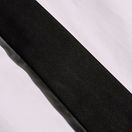 A Wren Neck-Tie Top, in black and featuring a sleek rectangular silhouette, is displayed diagonally across a white, slightly wrinkled surface, with contrasting light and shadows evoking the modern lines of New York Fashion Week.