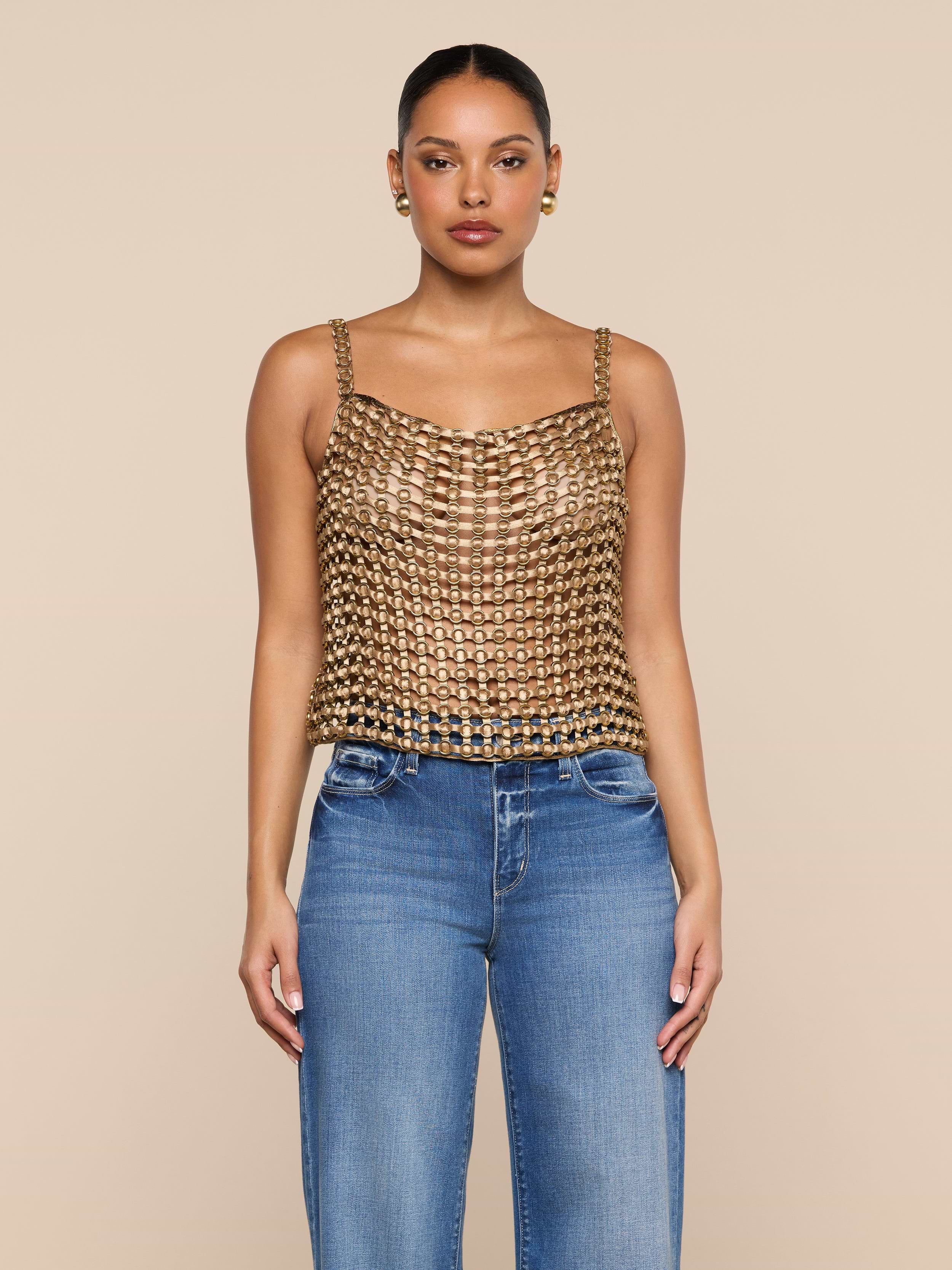 A woman stands facing forward, wearing the Joanette Embellished Tank with a gold chainmail-style design and blue jeans against a plain white background.