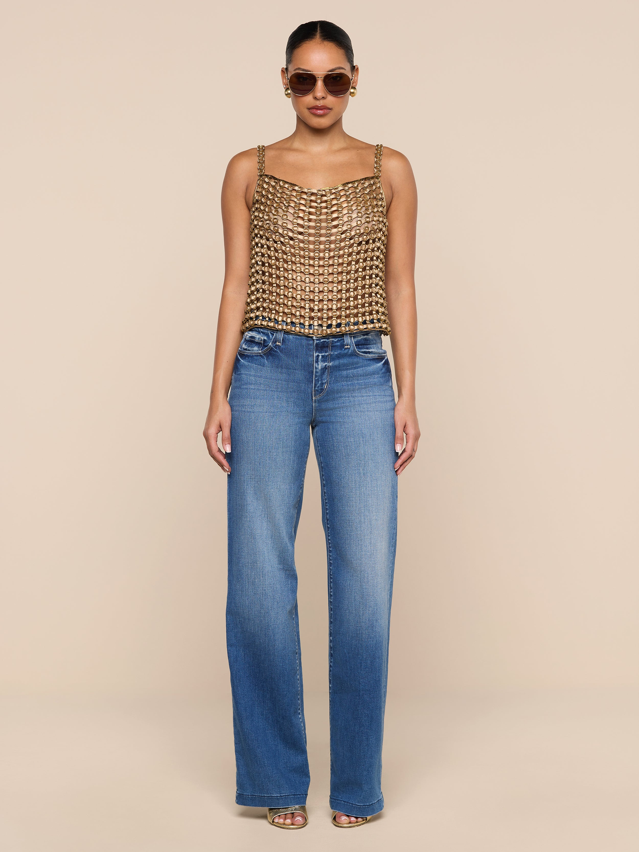 A woman wearing sunglasses, the Joanette Embellished Tank, blue high-waisted wide-leg jeans, and heeled sandals stands against a plain white background.
