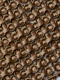 Close-up of interwoven gold metal rings and diagonal brown satin ribbons on the Joanette Embellished Tank, creating a textured, crisscross pattern reminiscent of handwoven craftsmanship.