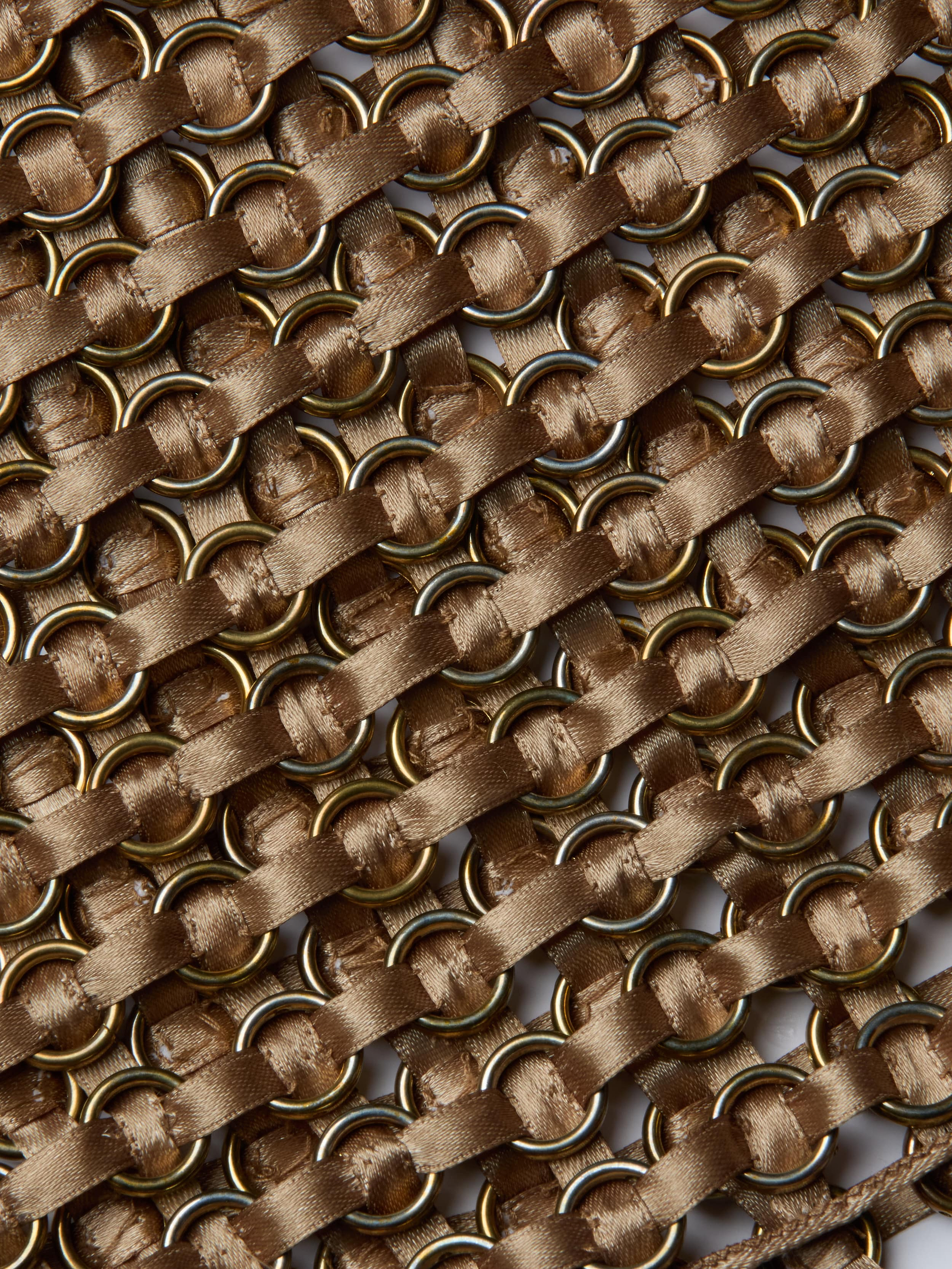 Close-up of interwoven gold metal rings and diagonal brown satin ribbons on the Joanette Embellished Tank, creating a textured, crisscross pattern reminiscent of handwoven craftsmanship.