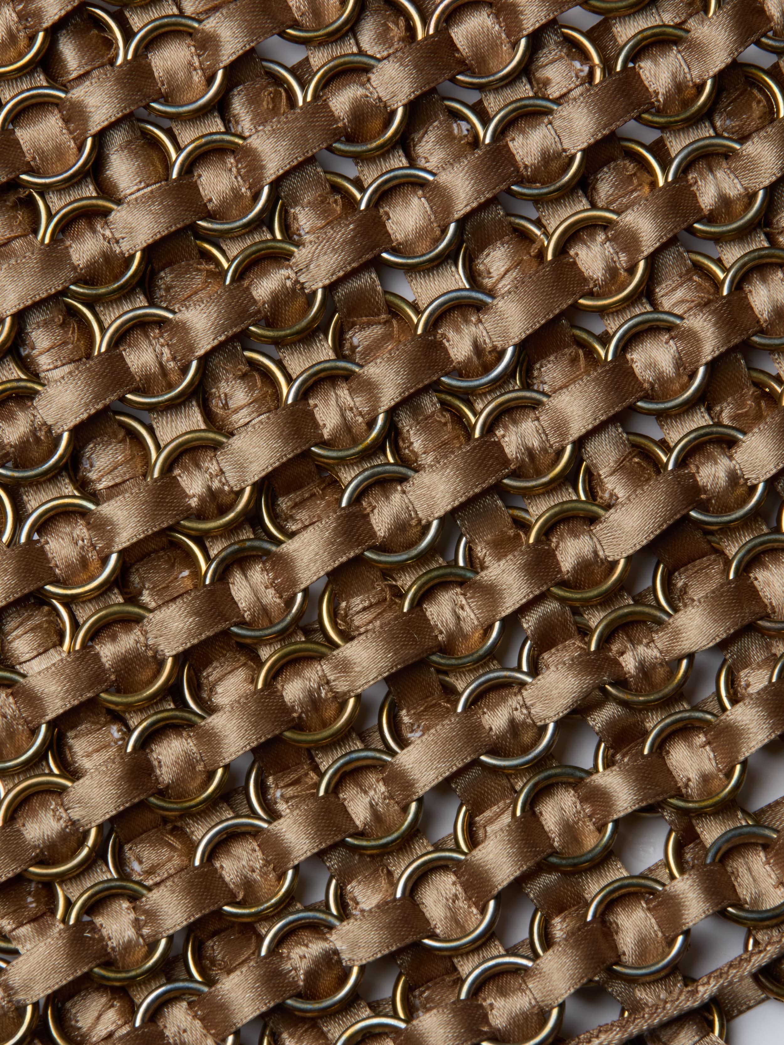 Close-up of interwoven gold metal rings and diagonal brown satin ribbons on the Joanette Embellished Tank, creating a textured, crisscross pattern reminiscent of handwoven craftsmanship.