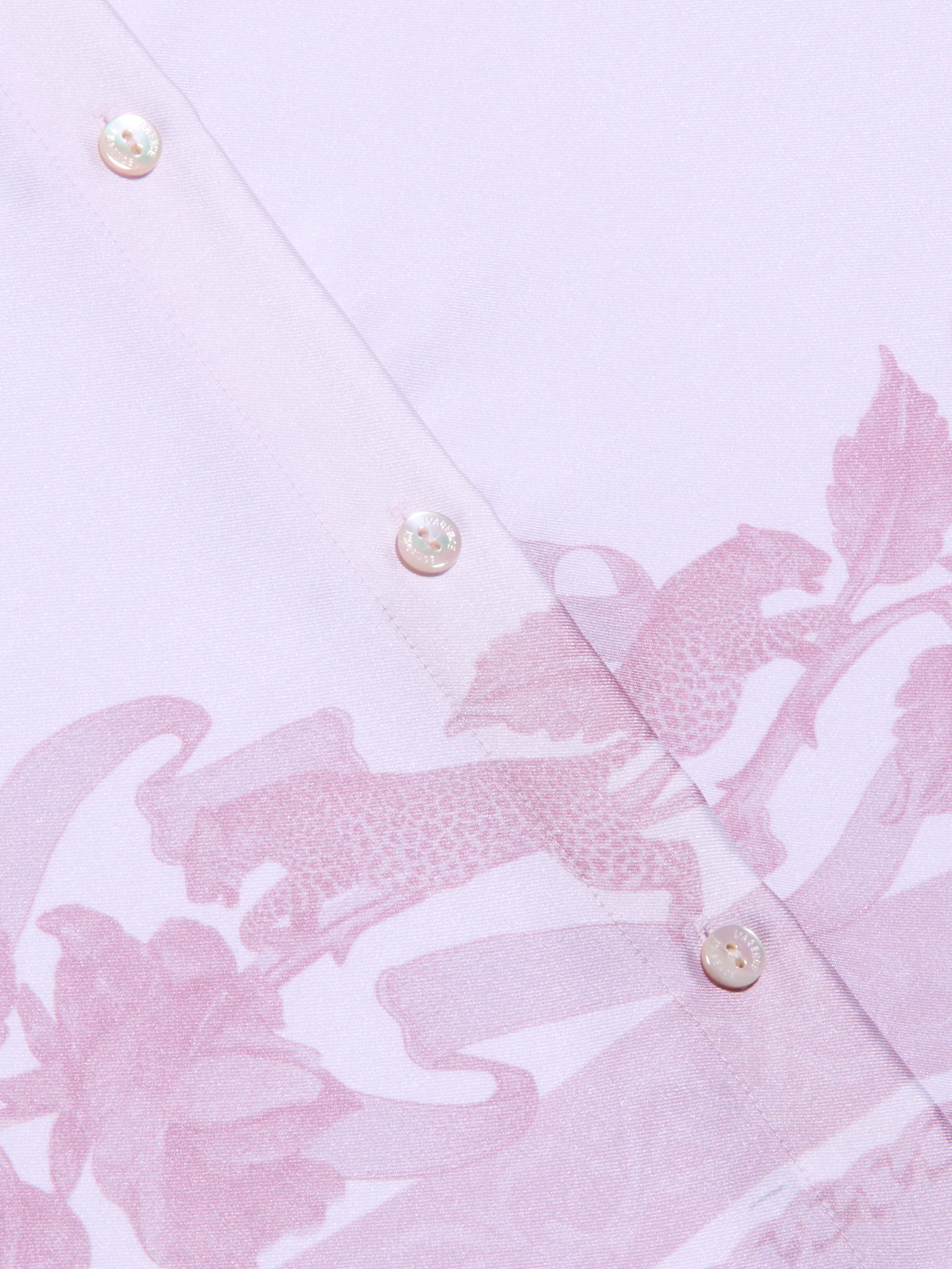 Close-up of the Judy Blouse, a light pink button-down shirt featuring two white buttons and a subtle leopard print and floral pattern in a slightly darker pink shade.