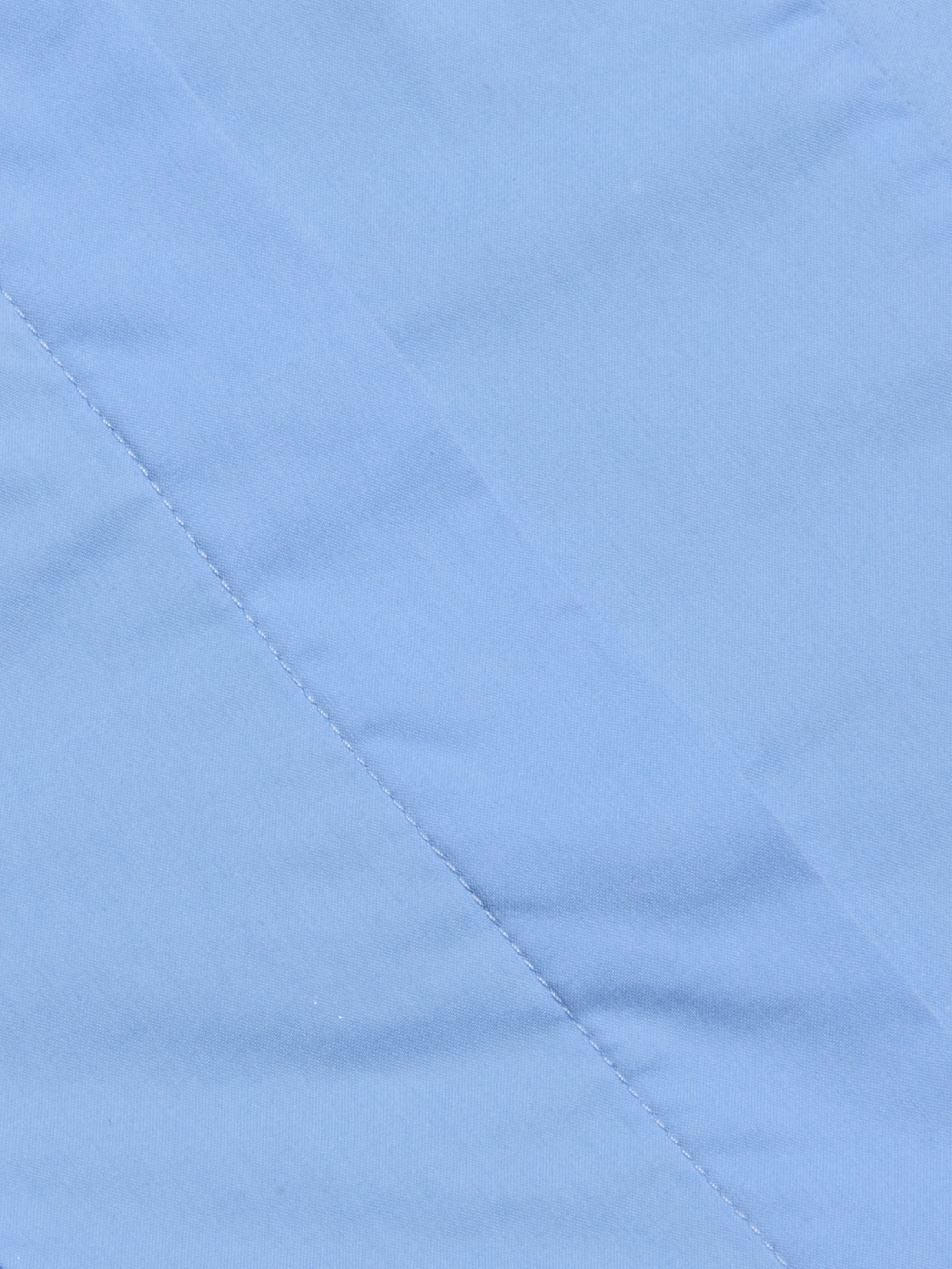 Close-up of light blue fabric with a diagonal seam and visible stitching detail, showcasing the smooth texture that makes it ideal for the Rina Poplin Halter Top.