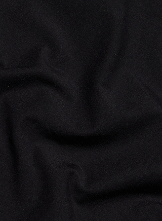 A close-up of the Sarai Off-The-Shoulder Top in black organic cotton fabric, featuring soft, subtle folds and gentle shadows that create a slightly wavy texture across the surface.