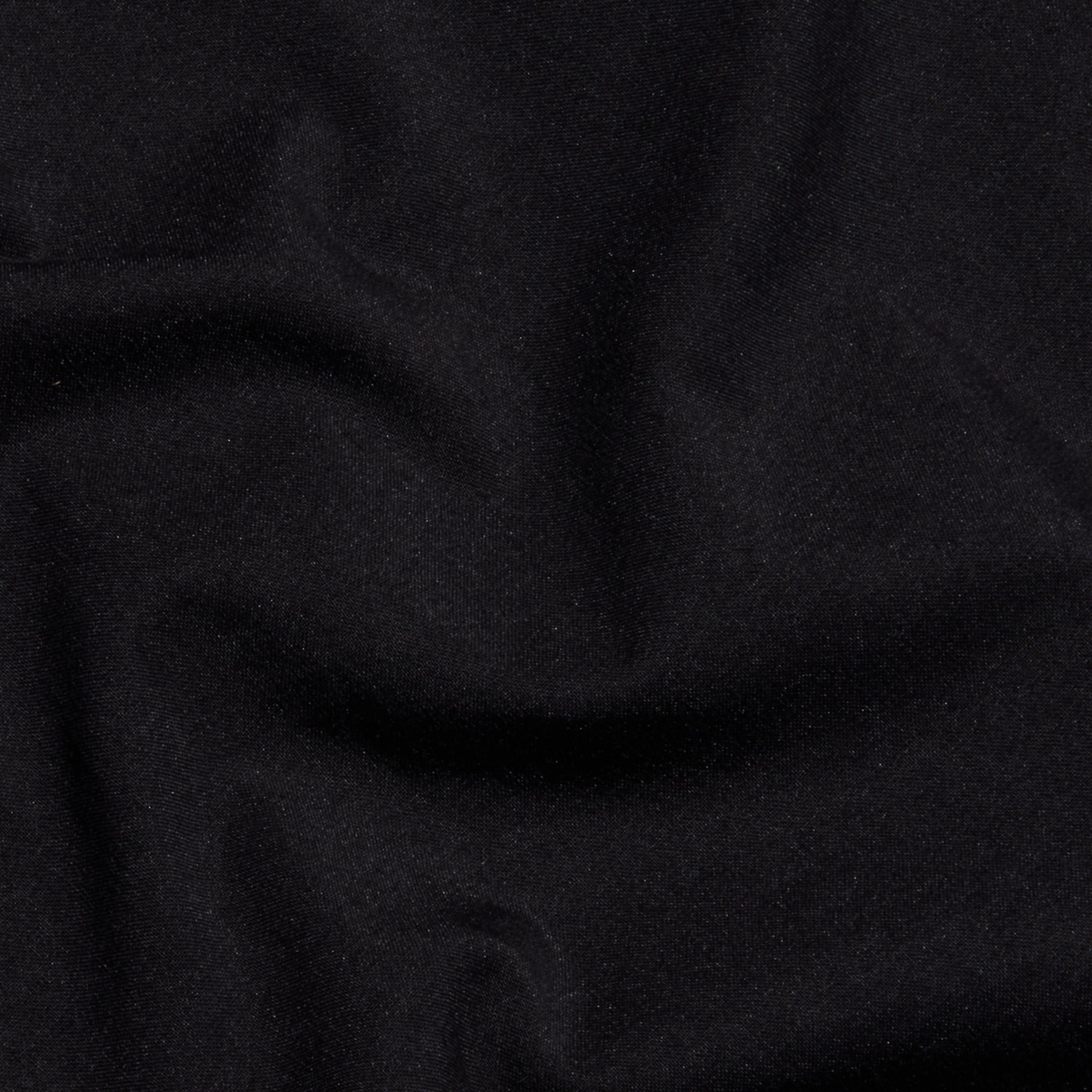 A close-up of the Sarai Off-The-Shoulder Top in black organic cotton-blend fabric, featuring subtle folds and wrinkles that highlight its smooth texture and soft sheen.